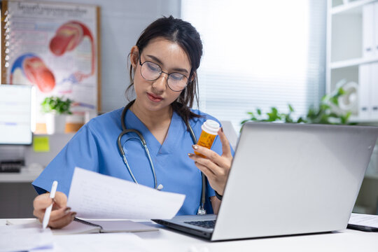 Female doctor, medicine bottle, prescription, laptop, clinic, health professional reviewing patient document with calm focus in modern medical office workspace