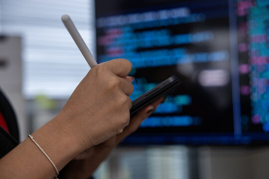Hand, stylus, smartphone, code, screen, programmer using mobile device near computer monitor with software script for digital work in office