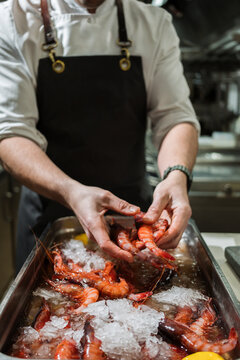 Chef preparing fresh raw shrimp on ice