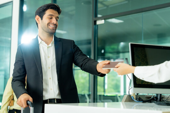 An airline employee assists a traveler with a passport at a modern airport counter illustrating attentive customer care and convenient travel support.