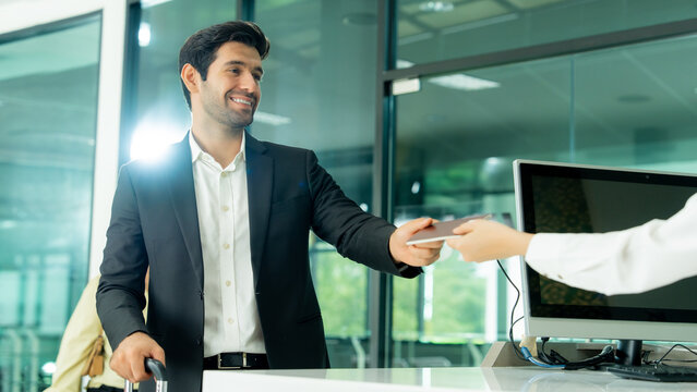 Airport staff hands a passport back to a smiling passenger at the check-in counter representing professional service and a smooth international travel experience.