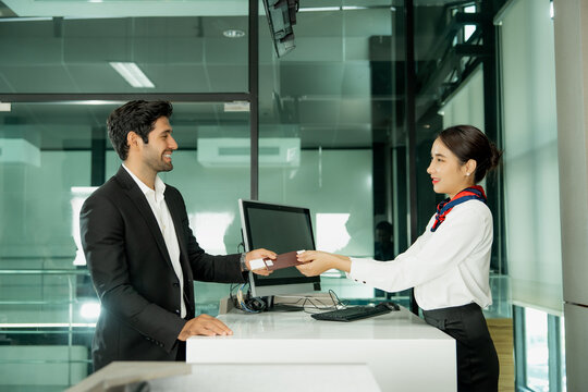 Airport staff assists a passenger at the check-in counter using digital technology to provide efficient travel service and a welcoming customer experience.
