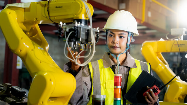 Engineer operating and inspecting robotic systems in a modern factory environment focused on automated manufacturing and industrial efficiency.