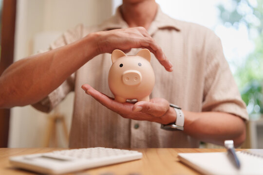 Man protecting a piggy bank symbolizes secure savings, budgeting, emergency funds, and long-term financial planning for future stability.