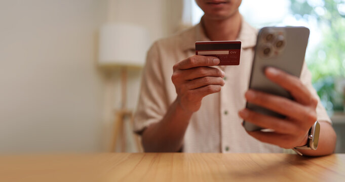 Customer holding a payment card and smartphone for online purchase, representing secure mobile payment, digital banking, cashless transactions, e-commerce shopping, and convenient checkout.