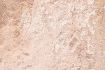 Fototapeta premium Abstract texture of an ancient weathered stone wall with beige plaster cracks