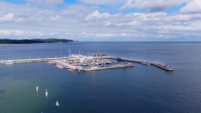 Aerial view of Sopot pier and marina filled with docked boats and sailing vessels on calm sea water in Poland during daytime.