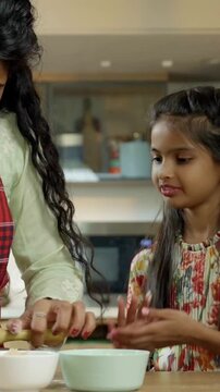 Indian Asian mother happily teaches her small daughter how to make roti or chapati, showcasing their skills with joy as they smile at the camera