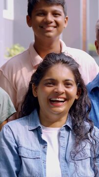 An Indian Asian family of four, parents in their forties and two kids, smiling while posing for a joyful portrait outside their lavish home, capturing a cherished moment together.