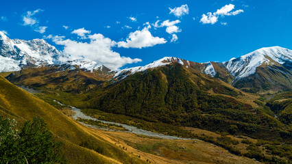 Naklejka premium Landscape photograph of snow covered mountains and glacier river valley viewed from Chkhutnieri pass in Svaneti Georgia.