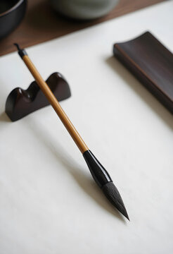 Traditional chinese calligraphy brush and wooden rest on white paper, asian art and cultural heritage, the tools are essential for learning and creating traditional chinese characters and artwork