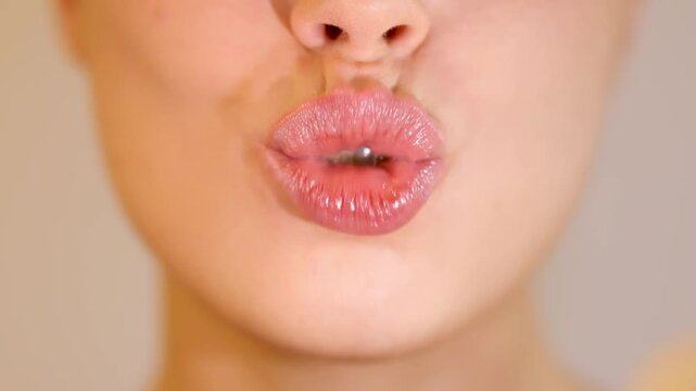 Close-up of young woman showing healthy white teeth and blowing a kiss