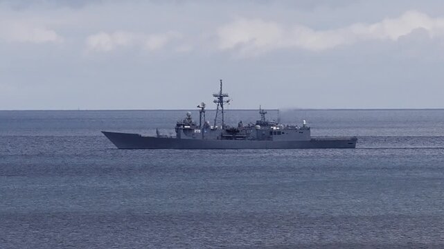 A military ship sails across the sea near Sopot in Poland. The grey warship moves steadily through the water under an overcast sky.