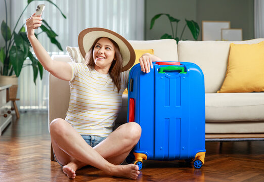 Woman taking selfie with suitcase before vacation