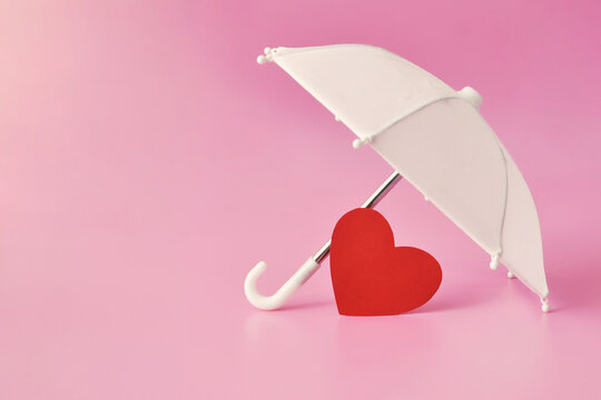 White umbrella protecting red heart. Love and emotional protection concept