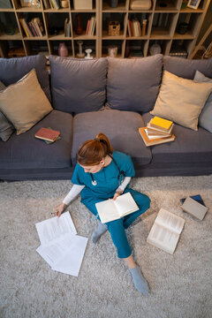 Medical student studying on floor with books and documents