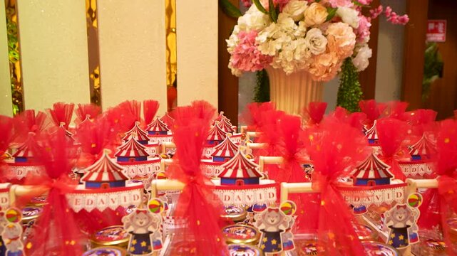 Festive birthday party decoration table with red gift favors and colorful balloon pillars