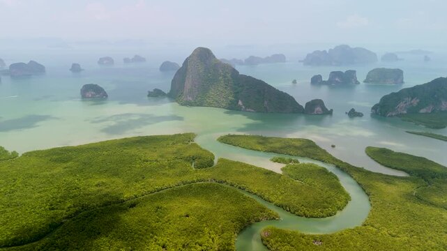 Lush green mangrove forest borders the turquoise waters of a tranquil bay filled with limestone karst islands near Samet Nongshe Viewpoint in Phang nga Thailand