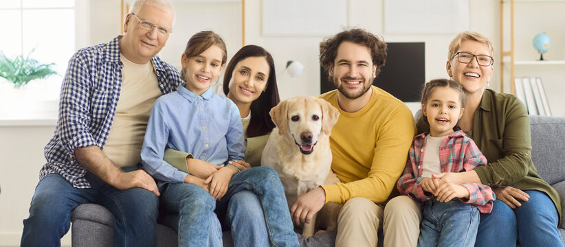 Family grandparents parents children and labrador dog together. Smiling multigenerational relatives sit on a cozy home sofa with a friendly pet. Concept shows unity, love, trust, care.