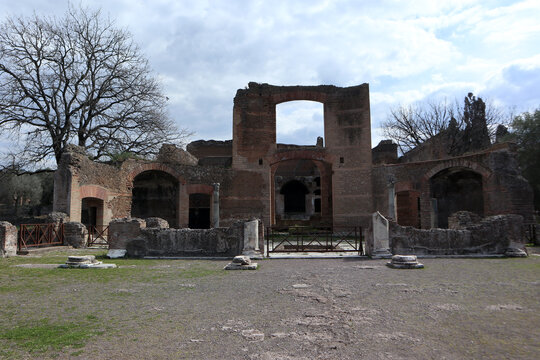Antiche rovine in mattoni delle Piccole Terme a Villa Adriana con archi romani e un albero spoglio sullo sfondo, Tivoli, Italia
