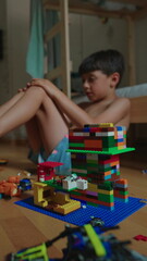 Fototapeta premium Boy building with construction blocks on bedroom floor, encouraging creativity, independent learning and imaginative childhood play