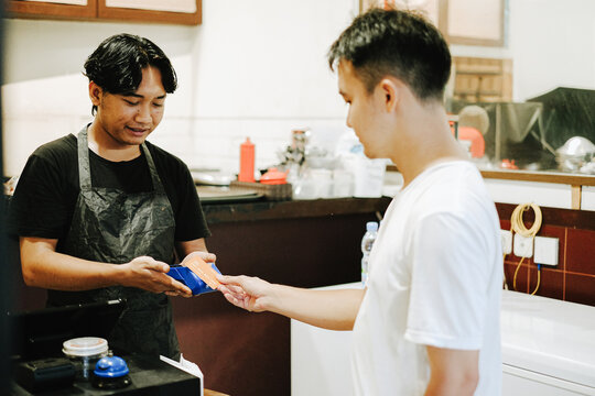 Southeast Asian cashier accepting contactless credit card payment from customer