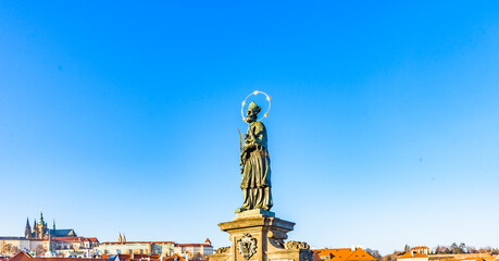 Fototapeta premium Statue of St John of Nepomuk on Charles Bridge in Prague, Czechia, UNESCO World Heritage Site, against clear blue sky