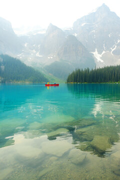 Several Groups of People in Red Canoes Floating on Brilliant Blue Lake in the Wilderness Mountains Enjoying Nature Outdoors