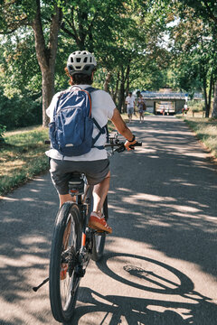 Active woman cycling on a sunny Sunday afternoon along a historic tree-lined avenue in Monrepos Park. Ludwigsburg, Baden-W&uuml;rttemberg, Germany.