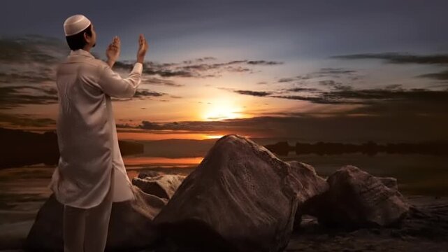 Man and his loyal dog watching the sunset on a sandy beach.