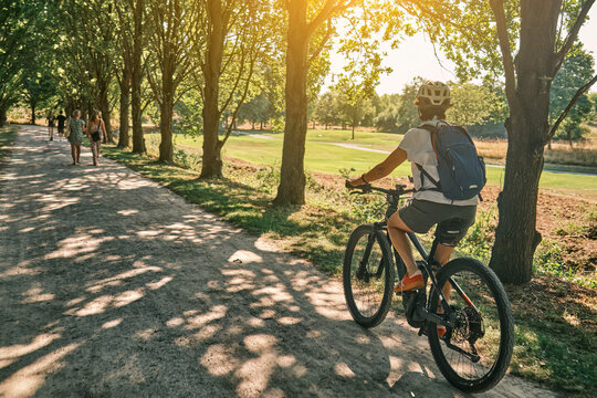 Active woman cycling on a sunny Sunday afternoon along a historic tree-lined avenue in Monrepos Park. Ludwigsburg, Baden-W&uuml;rttemberg, Germany.