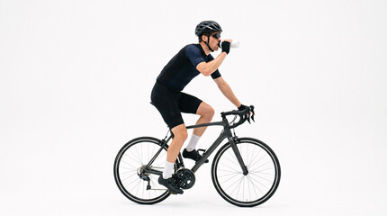 Fototapeta premium Male cyclist in full cycling gear on a road bike, taking a drink from a water bottle against a clean white background.