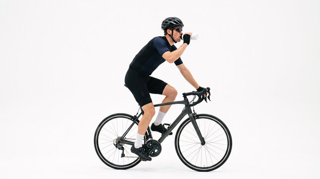 Male cyclist in full cycling gear on a road bike, taking a drink from a water bottle against a clean white background.