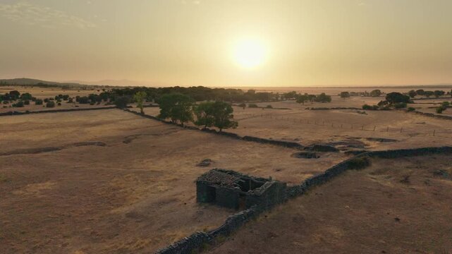 Drone flying over a dry dehesa landscape in Salamanca, Spain, showing the effects of drought, water scarcity, and heatwave during a beautiful summer sunset