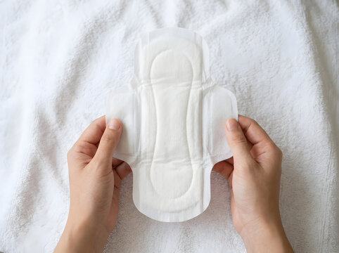 Female Hands Holding Unwrapped Sanitary Napkin Pad over White Towel | Close Up of Hands Holding Clean White Hygiene Sanitary Pad | Woman Hands Holding Soft Cotton Sanitary Napkin Pad