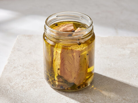 Preserved tuna fillet chunks in olive oil inside a clear glass jar