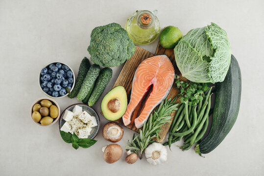 Top view of fresh whole foods for healthy eating, balanced nutrition and Mediterranean cuisine, with colorful salmon creating a vibrant accent.