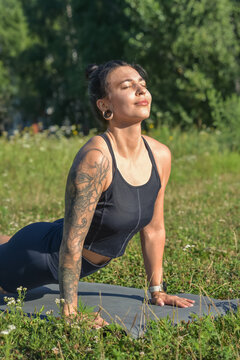 Young woman practicing Surya Namaskar yoga outdoors