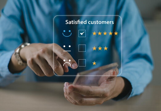 The hand is giving a five-star rating. The business person selects the smiley face icon on the virtual screen to express their satisfaction with the service. The rating received is very impressive.