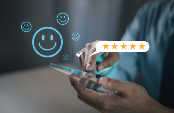 The hand is giving a five-star rating. The business person selects the smiley face icon on the virtual screen to express their satisfaction with the service. The rating received is very impressive.