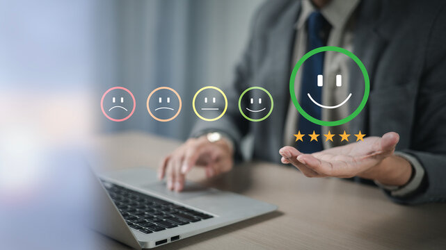 The hand is giving a five-star rating. The business person selects the smiley face icon on the virtual screen to express their satisfaction with the service. The rating received is very impressive.