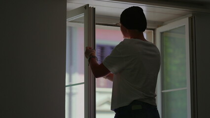 Fototapeta premium Woman cleaning open window at home, highlighting household routine, hygiene and domestic care