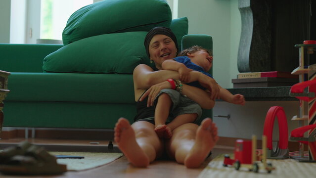 Mother hugging laughing toddler during play at home, highlighting joyful interaction, family bonding and emotional connection