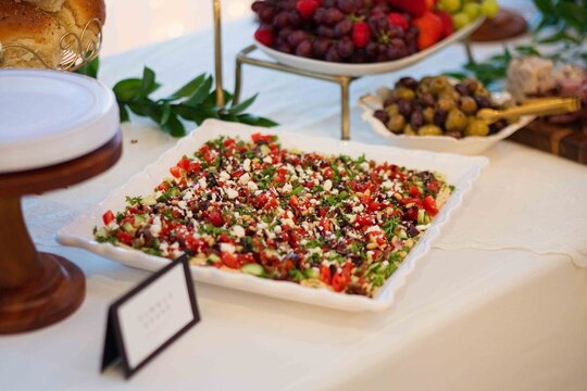tabbouleh salad arranged on a porcelain plate at a banquet setting with bread rolls and fruit platt.
