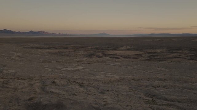 An Aerial shot of an vast desert and distant mountains at dusk near Sevier Lake, Utah, USA