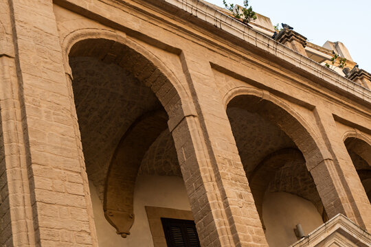 Bari Italy historic arcade with rounded stone arches on old town building facade, classical Mediterranean architecture and sandstone colonnade in southern Italy