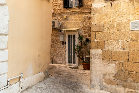 Bari old town narrow alley with historic stone buildings and secured door with iron bars, southern Italy architecture and Mediterranean urban heritage