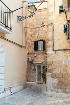 Bari Italy old town narrow alley with historic stone buildings, iron gate door and ornate street lamp in traditional southern Italian architecture