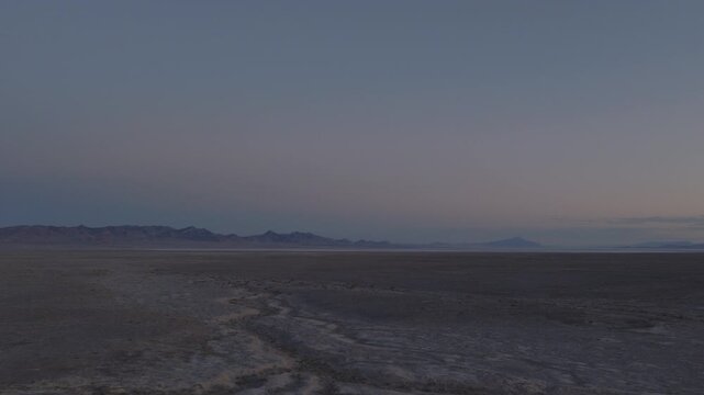 An Aerial shot of an vast desert and distant mountains at dusk near Sevier Lake, Utah, USA