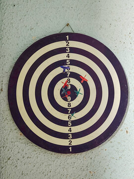 Dartboard with darts hitting target and missing
